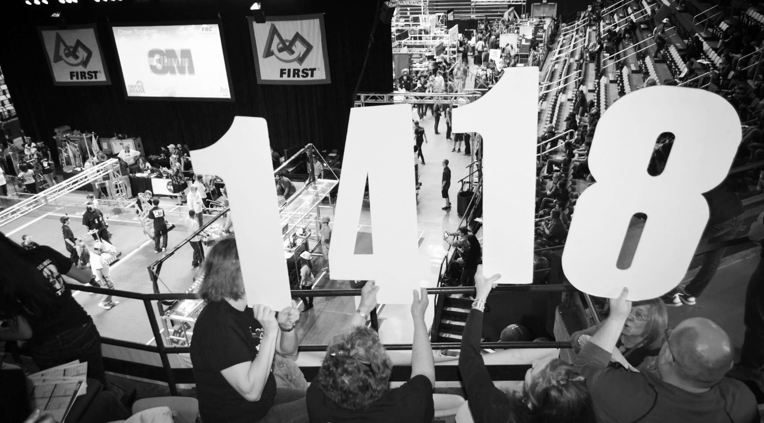 A black and white picture of team members holding up the numbers 1418.