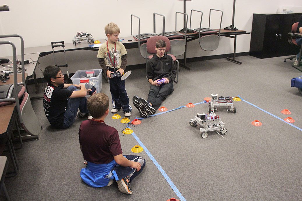 Children and a team member driving robots.
