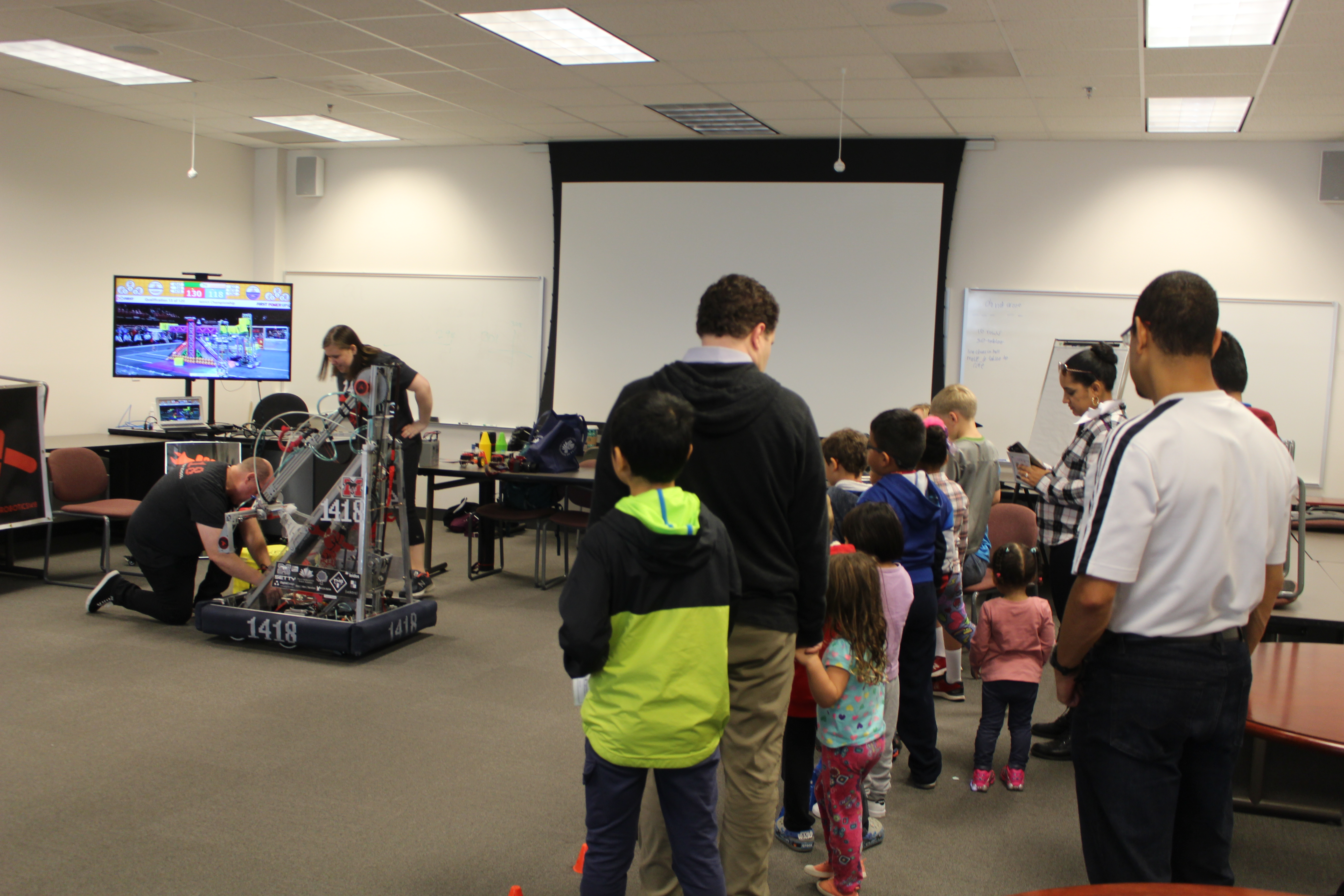 A group watches as the robot receives repairs.