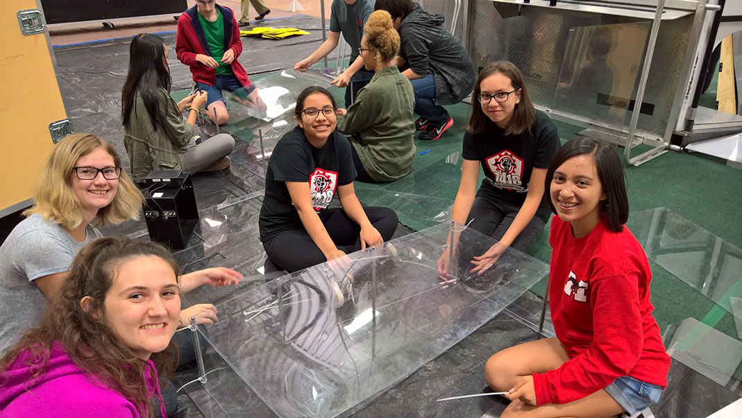 Team members smiling around a piece of plexiglass.
