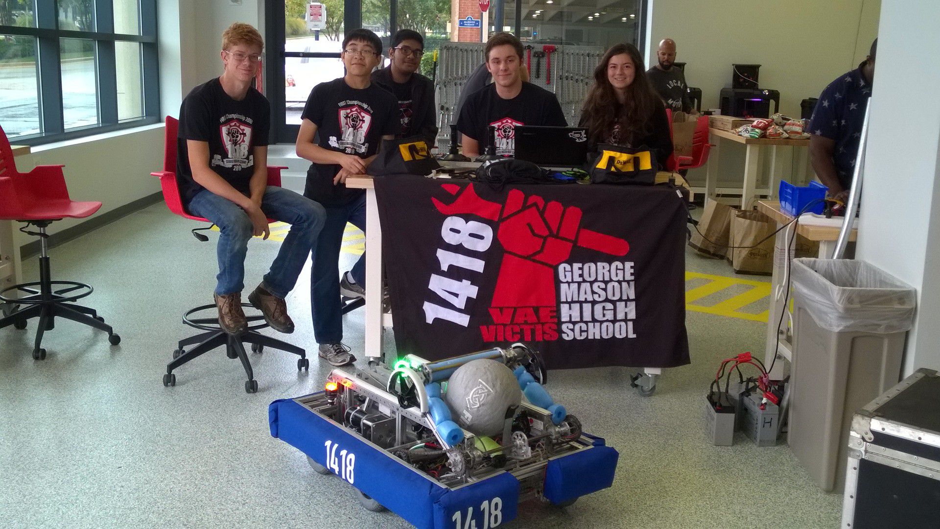The team posing behind a 1418 banner with the robot in front.
