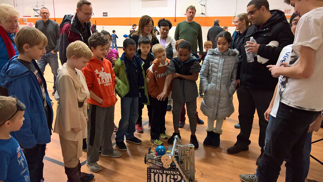 Children and parents huddled around a small robot.