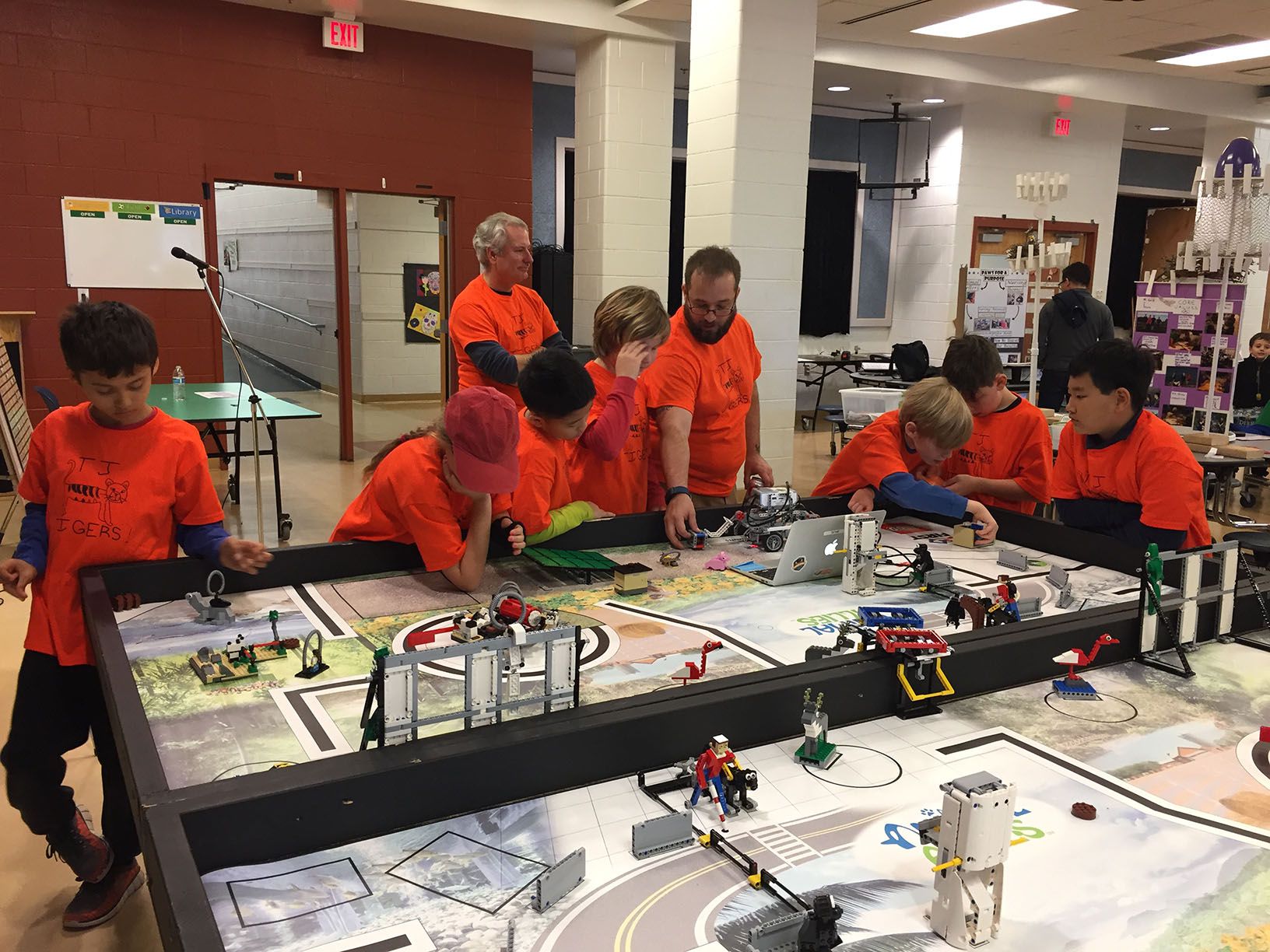 Students tinkering on their robot in the miniature pit.