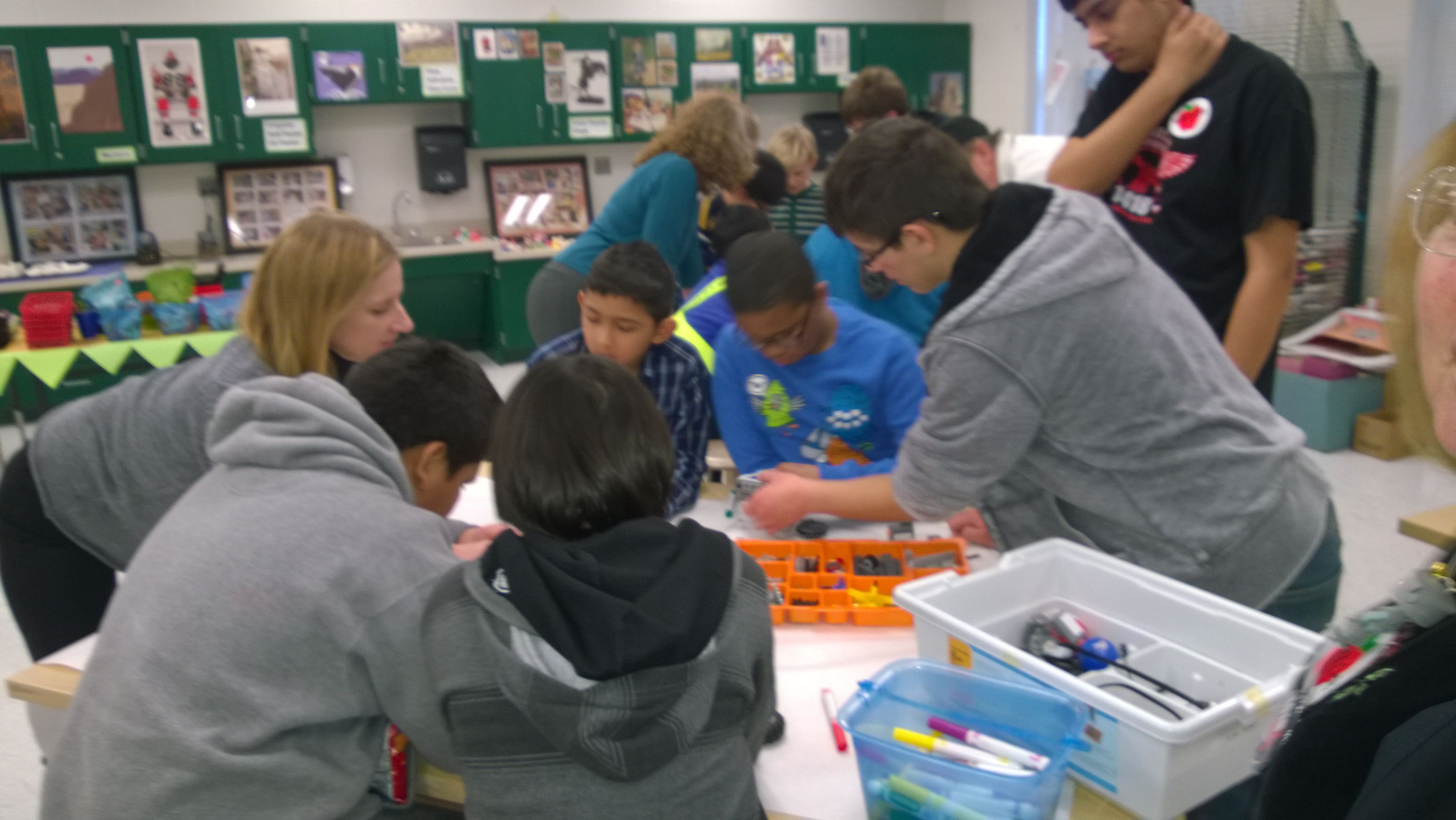 Team member holds a robot part, showing it to children.