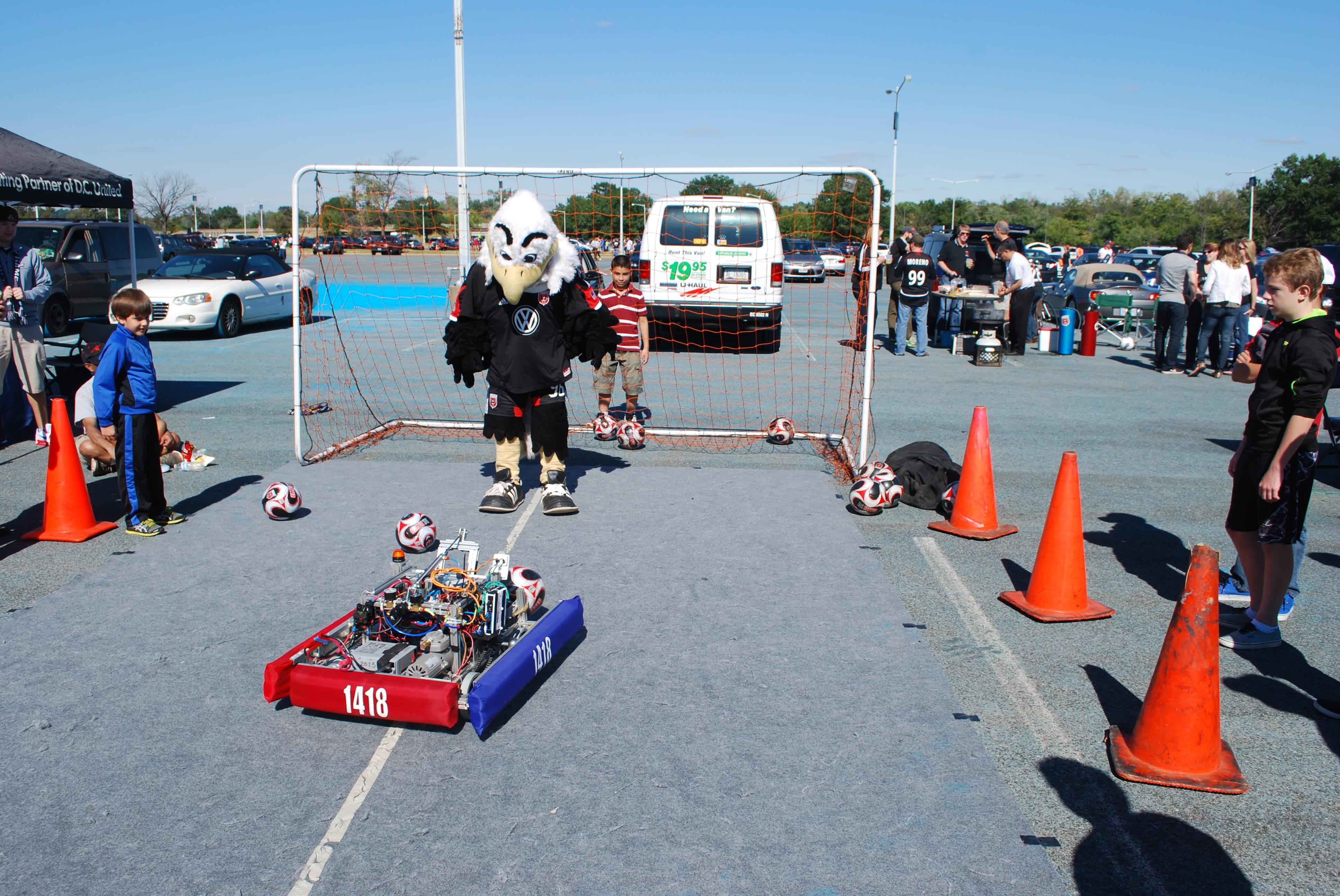 An eagle mascot looking at the 1418 robot.