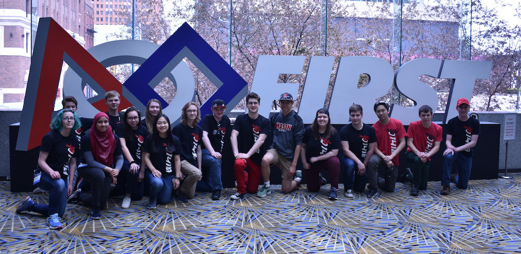 The team at the 2019 FIRST World Championships, in front of the FIRST Logo at the Cobo Center in Detroit.